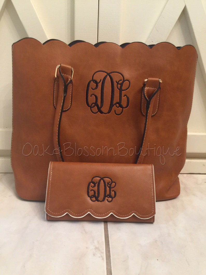 Puede incluir: Un bolso tote de cuero marr&oacute;n y una cartera a juego con bordes festoneados y un dise&ntilde;o de monograma. El monograma es "GDL" en hilo negro.