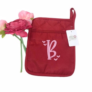 Può includere: Guanto da forno trapuntato rosso con una lettera "B" ricamata in rosa e cuori. Il guanto ha un anello per appenderlo e una tasca. L'etichetta dice "Oak Blossom".