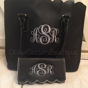Puede incluir: Bolso tote negro y cartera a juego con bordes festoneados. Ambos art&iacute;culos presentan un monograma bordado en plata "JSR".