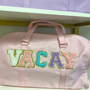 Pu&ograve; includere: Borsa da viaggio rosa con la parola "VACAY" scritta in lettere colorate e scintillanti.