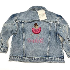 May include: Light blue denim jacket with pearl embellishments on the sleeves. The jacket features an embroidered ballerina design and the name "Scarlett" in pink thread.