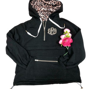 May include: Black hooded sweatshirt with a leopard print lining. The sweatshirt has a zipper closure and a large pocket on the front. The sweatshirt is monogrammed with the letters "DBD" in gold thread.