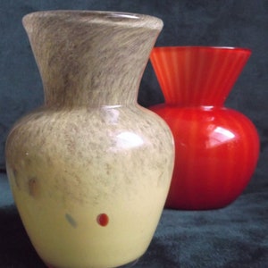 May include: Two glass vases, one with a mottled brown and yellow glaze and the other a solid red glaze.