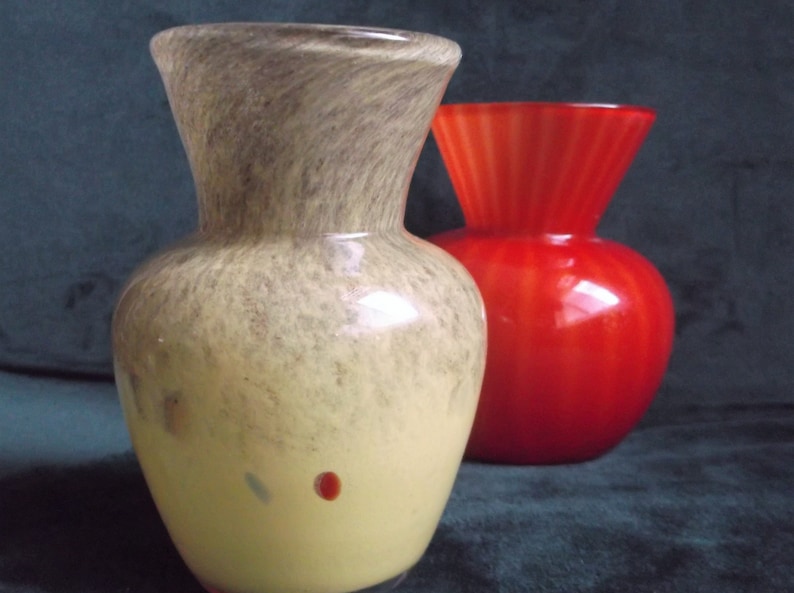 May include: Two glass vases, one with a mottled brown and yellow glaze and the other a solid red glaze.