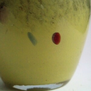 May include: A yellow glass vase with a red and blue swirl design.