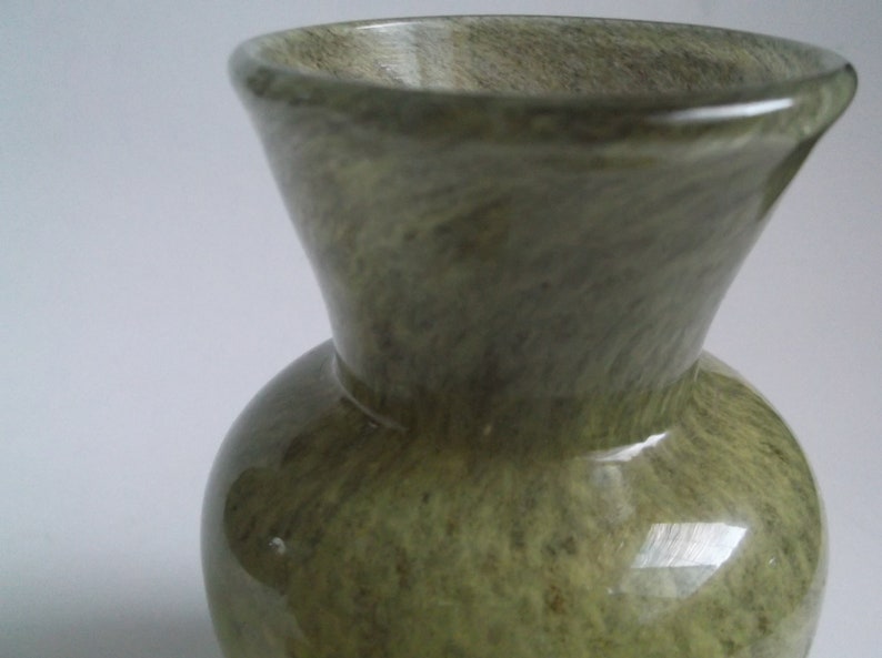 May include: A green glazed ceramic vase with a marbled pattern. The vase has a wide mouth and a rounded body.