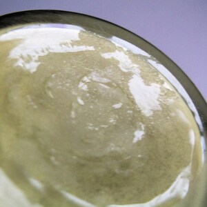 May include: Close-up of the bottom of a clear glass bottle with a textured surface.