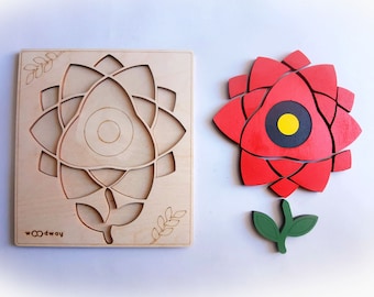 Op de afbeelding: Houten puzzel met een rode bloem met een zwart en geel centrum. De bloem is gemaakt van meerdere stukken die in elkaar passen. De puzzel bevat ook een houten basis met een uitsnijding van de bloem.