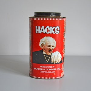 Peut inclure: Boîte en métal rouge et blanche avec un couvercle noir. La boîte représente un homme avec un mouchoir blanc sur la bouche. Le texte sur la boîte indique "Hacks" et "Fabriqué par Barker & Dobson Ltd., Liverpool, Angleterre."