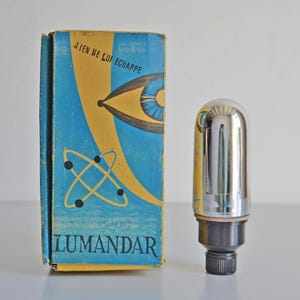 May include: Vintage Lumandar vacuum tube with its original box. The box is blue and yellow with the text "Aien Ne Lui Echappe" and "Lumandar". The tube is silver and black.