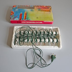 Pode incluir: Conjunto de luzes de Natal vintage com 20 lâmpadas transparentes em um fio verde. As luzes estão em uma bandeja de isopor, com a caixa original com ilustrações de velas. A caixa diz "20 Kerstboomverlichting".
