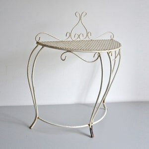 Peut inclure: Table d'appoint en métal blanc avec un design décoratif enroulé et un plateau en treillis métallique.
