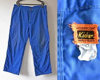 May include: A pair of blue work pants with a label that reads "Hobbycoat Kidur Made in France".