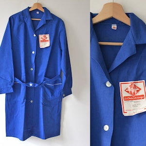 May include: A blue work coat with white trim and a label that reads "La Chaine des Usines" in red lettering.