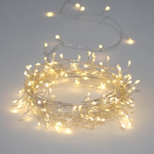 Op de afbeelding: Een string met warm witte kerstverlichting met een zilveren draad. De lampjes zijn in een cirkel opgerold.