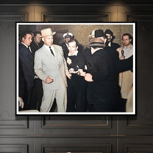 Puede incluir: Una fotografía en blanco y negro de un grupo de hombres con trajes y sombreros. Los hombres están de pie en una habitación con una pared de ladrillo en el fondo. El hombre en el centro de la imagen lleva un sombrero y un traje. Está mirando a la cámara. Los otros hombres lo miran o miran algo fuera de cámara.