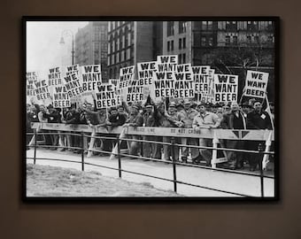 May include: Black and white framed print of a historical protest. The image shows a crowd of people holding signs that read "We Want Beer". The print is displayed in a bar setting with a neon sign that says "Good People Good Drinks Good Times".