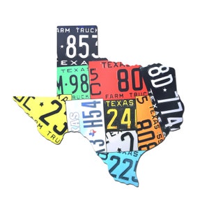 May include: A colorful Texas state outline made of vintage license plates. The plates are mostly yellow, red, blue, and green, with black numbers and letters. The plates have the words "Texas", "Farm Truck", and "Texas" on them.