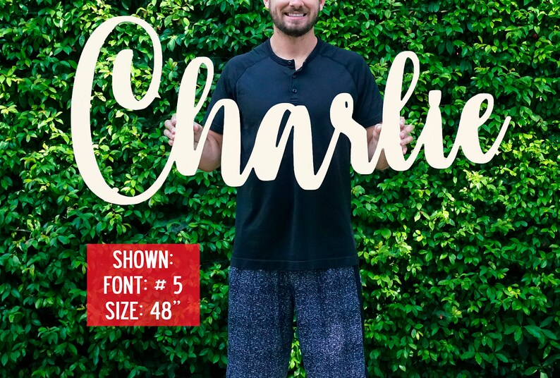 May include: A white wooden sign with the name "Charlie" written in a cursive font. The sign is 48 inches tall and is being held by a person. The sign is shown in font #5.