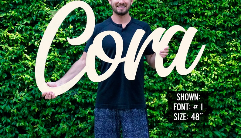 May include: White wooden sign with the name "Cora" in a cursive font. The sign is 48 inches tall. Shown: Font #1, Size: 48"
