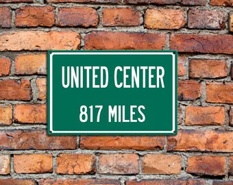 Puede incluir: Un letrero verde con texto blanco en una pared de ladrillo. El letrero dice "UNITED CENTER 817 MILES".