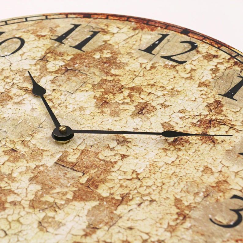 Puede incluir: Una esfera de reloj de estilo vintage con n&uacute;meros romanos y agujas negras. La esfera tiene un aspecto desgastado y envejecido con un acabado de pintura blanca agrietada y astillada.
