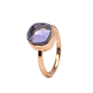 May include: A rose gold ring featuring a large, faceted, square-cut lavender gemstone. The ring has a simple, elegant design with a smooth, polished band. The gemstone is set in a bezel setting, showcasing its color and cut.
