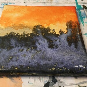 May include: A watercolor painting on canvas depicting a sunset over a forest. The sky is a vibrant orange and yellow, with a layer of clouds above a dark green forest. The bottom of the painting is a dark blue and purple color, with hints of gold.