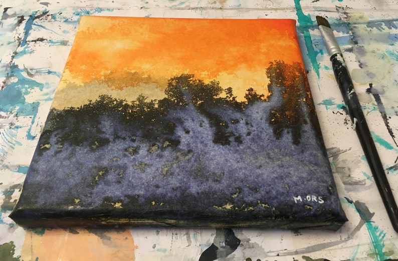 May include: A watercolor painting on canvas depicting a sunset over a forest. The sky is a vibrant orange and yellow, with a layer of clouds above a dark green forest. The bottom of the painting is a dark blue and purple color, with hints of gold.