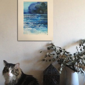 May include: A framed watercolor painting of a seascape with blue and green hues. The painting depicts a dark blue sky with a few clouds and a light blue ocean with white waves.