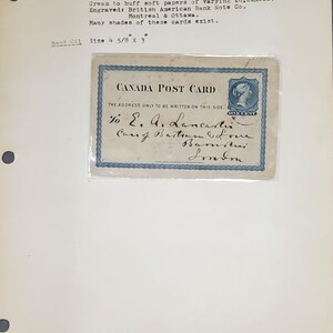 May include: A vintage Canadian postcard with a blue border and the text "CANADA POST CARD" printed in black. The address side of the card has a one-cent stamp featuring Queen Victoria. The card is addressed to "E. A. Lancast" with a handwritten message.