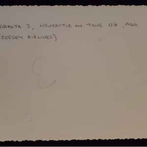 May include: A vintage photograph with a scalloped edge. Handwritten text reads "DAKOTA 3, NEWCASTLE ON TYNE U.K., 1960" and "(JERSEY AIRLINES)". The image is on a light-colored paper.