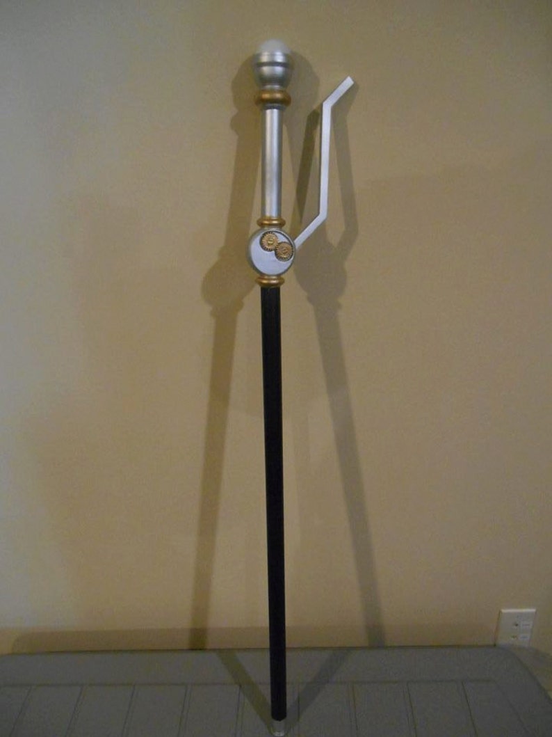 May include: A silver and black walking stick with a decorative top and a silver handle. The stick has a black shaft and a silver tip.