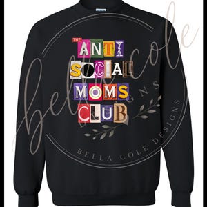 以下が含まれることがあります： 黒色のスウェットシャツ。前面中央に「THE ANTI SOCIAL MOMS CLUB」の文字が、切り抜いたようなカラフルな文字でデザインされています。クルーネックと長袖のデザインです。