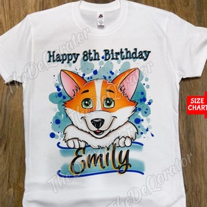 Puede incluir: Camiseta blanca con un perro corgi de dibujos animados que lleva un pañuelo azul y el texto "Happy 8th Birthday Emily".