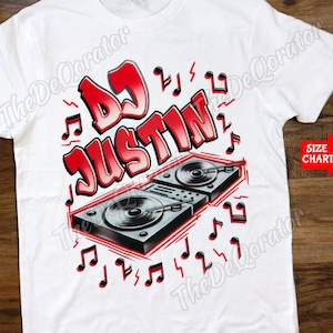 May include: White t-shirt with a red and black graphic design of a DJ mixer with the text "DJ Justin" and musical notes.