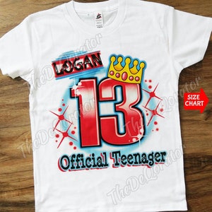 May include: White t-shirt with a red and blue airbrushed design featuring the number 13, a crown, and the text "Logan" and "Official Teenager".