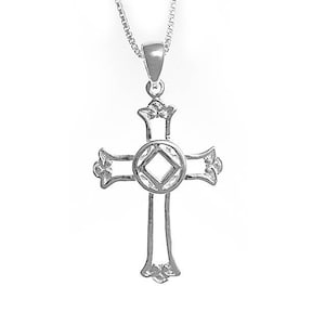 Puede incluir: Un collar de cadena de plata con un colgante de cruz de plata. La cruz tiene un diseño decorativo con un círculo en el centro.