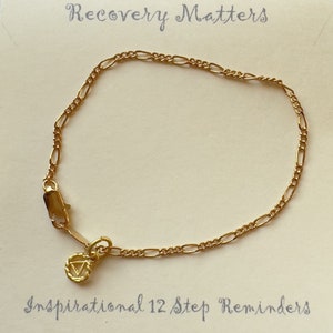 Può includere: Braccialetto a catena dorata con un piccolo ciondolo con un simbolo e il testo "Recovery Matters" e "Inspirational 12 Step Reminders".