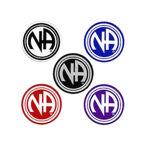 May include: Five round stickers with the letters NA in a circle. The stickers are in different colors: black, white, gray, red, and purple.