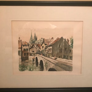 May include: A watercolor painting of a European town with a bridge over a river. The buildings are in shades of brown and gray, and the sky is a light blue. There are trees and bushes in the foreground.