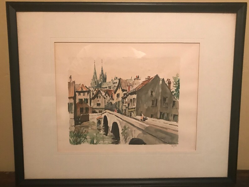 May include: A watercolor painting of a European town with a bridge over a river. The buildings are in shades of brown and gray, and the sky is a light blue. There are trees and bushes in the foreground.