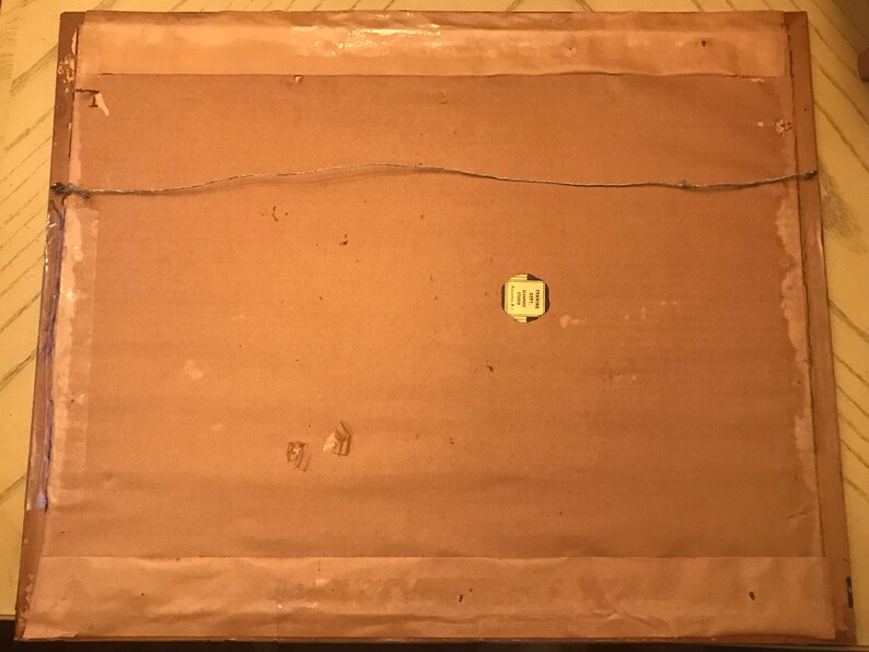 May include: The back of a framed picture with a brown cardboard backing. A small yellow label is attached to the cardboard. The label has text that is too small to read.