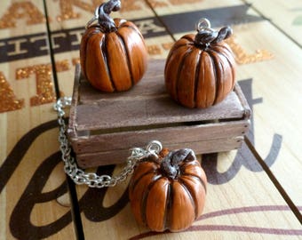 May include: Three brown clay pumpkin charms, one on a silver chain necklace. The pumpkins have a textured surface and are about 5 cm tall.