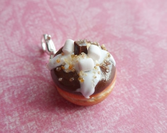 Peut inclure: Un mini beignet glacé au chocolat, avec un glaçage blanc et un carré de chocolat surmonté de mini guimauves. Le beignet est un charme sur une chaîne argentée.