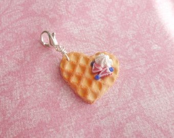 Peut inclure: Un charme en forme de cœur en gaufre avec du glaçage blanc et des accents de fruits roses et bleus. Le charme est attaché à un fermoir argenté.