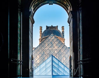 May include: A view of the Louvre Museum in Paris, France, with the iconic glass pyramid reflected in a puddle of water.