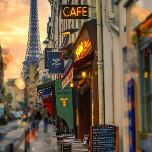 May include: A Parisian cafe with a cafe sign, a menu board, and tables and chairs set up outside. The Eiffel Tower is visible in the background.