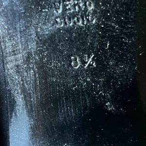 May include: Close-up of a black shoe sole with the size 8 1/2 embossed. The sole has a textured surface and the brand name "VERO CUOIO" is also visible. The shoe appears to be well-worn.