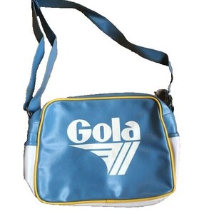 May include: A blue shoulder bag with a white and yellow trim. The bag features the white text "Gola" and a white chevron design. The bag has a blue shoulder strap.
